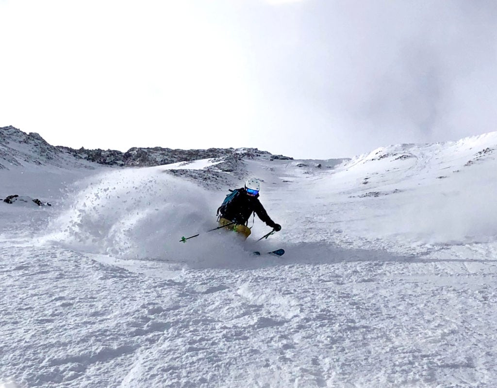 downhill skier going down a steep, snowy, mountain slope