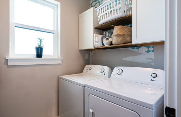 488 Countryside Lane - laundry room with a window to the left, washer and dryer to the right, with 2 cabinets and a shelf between them above. there is some partially removed wallpaper above the washer and dryer
