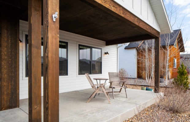 488 Countryside Lane - covered front patio made of concrete. two chairs and a small table are set-up on there, with two windows behind it.