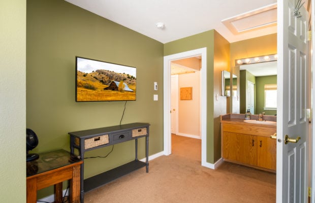 79 Starlight Drive - tv and console table in bedroom #1, with bathroom sink to the right of entry door. walls are green.
