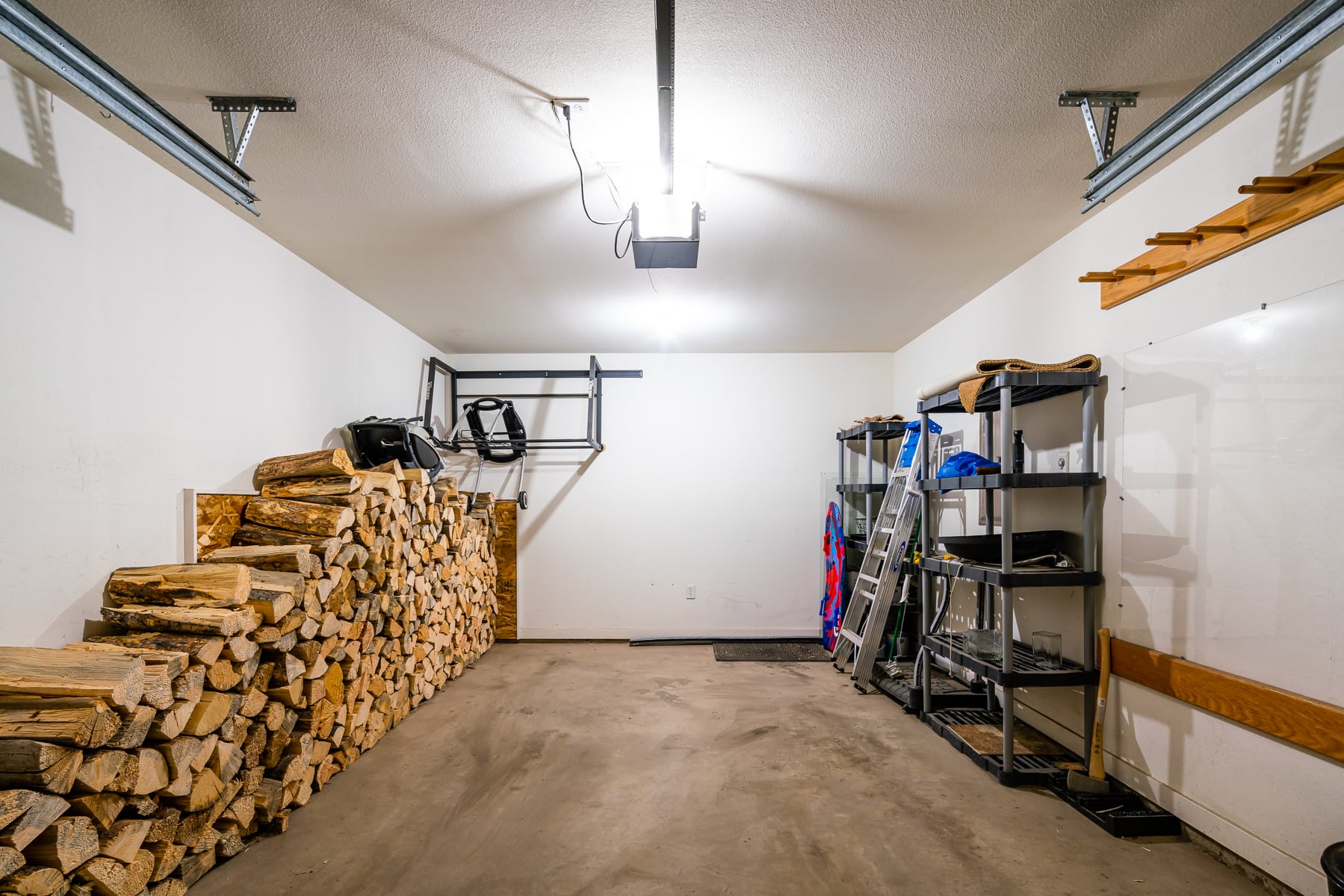 79 Starlight Drive inside the attached garage with a stack of firewood along the wall to the left, and plastic shelves along the right