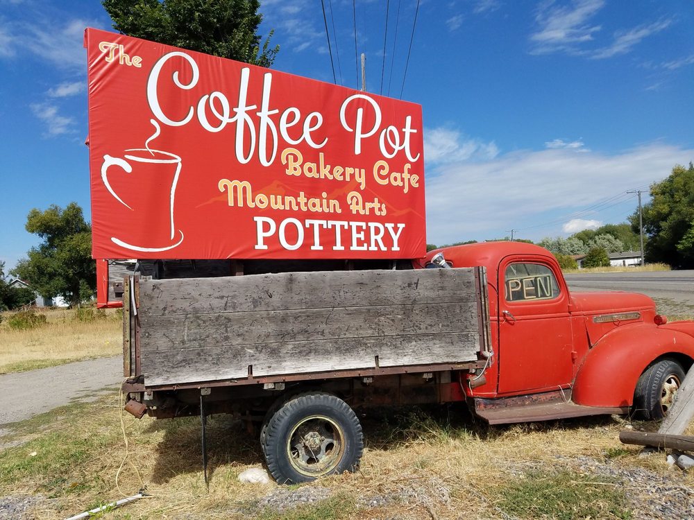 Vintage pick up truck with billboard in the back reading, 'The coffee pot bakery Café. Mountain arts pottery"