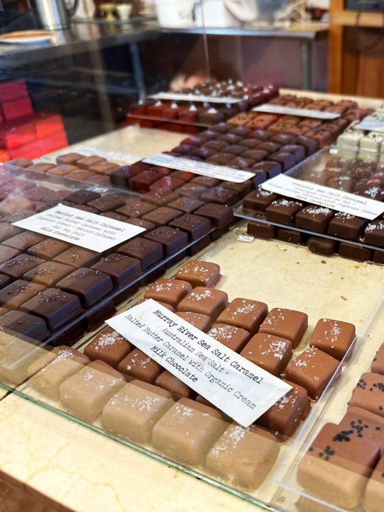 Photo of an assortment of chocolates behind glass inside of the chocolate Shoppe