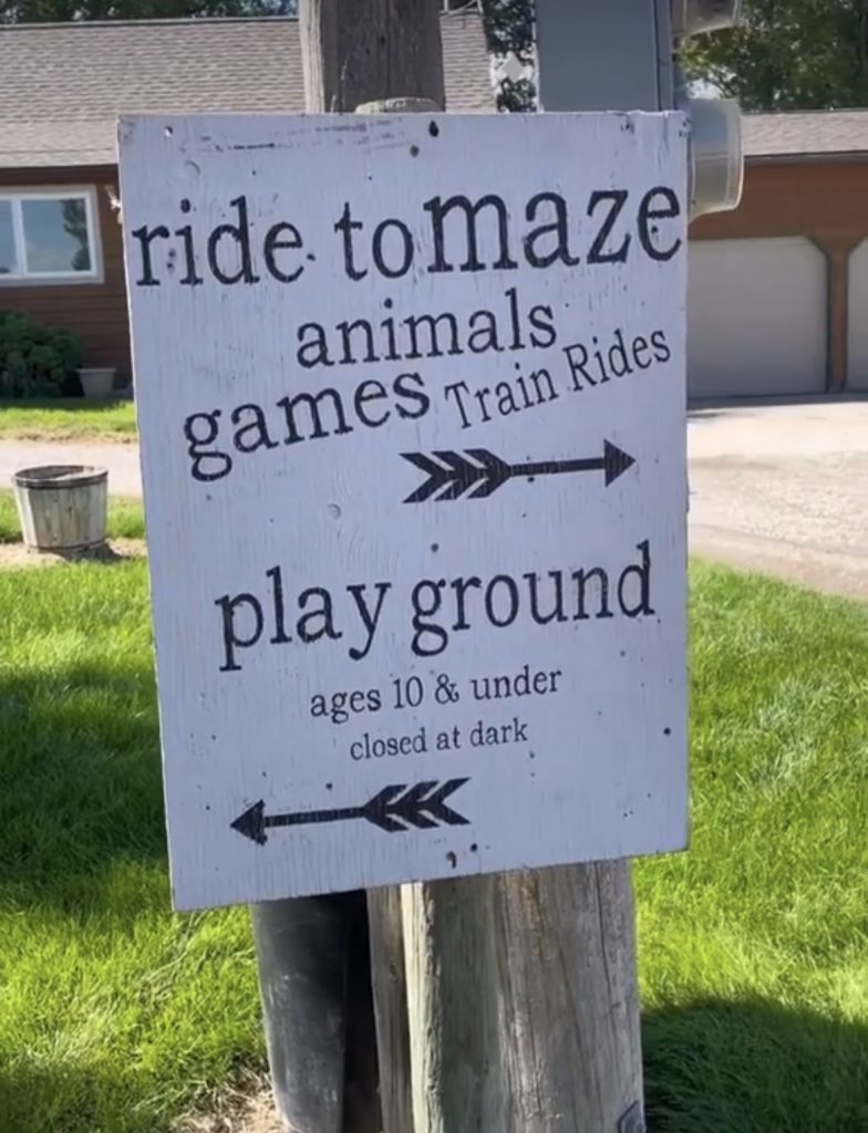 sign for montana corn maze that reads, "ride to maze animals games train rides playground ages 10 and under closed dark"
