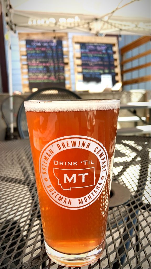 Pint glass of beer sitting on a patio table outside of Bozeman brewing Company