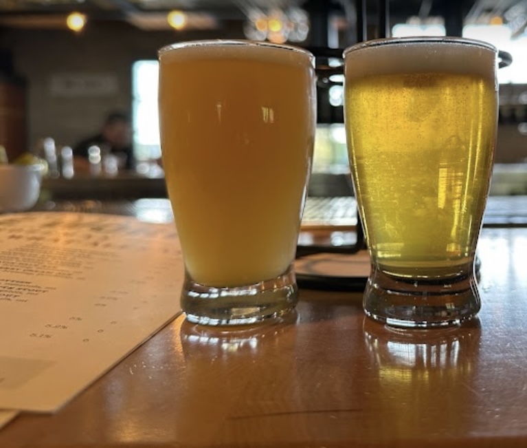 Two small glasses of beer sitting on the bar inside Montana ale Works