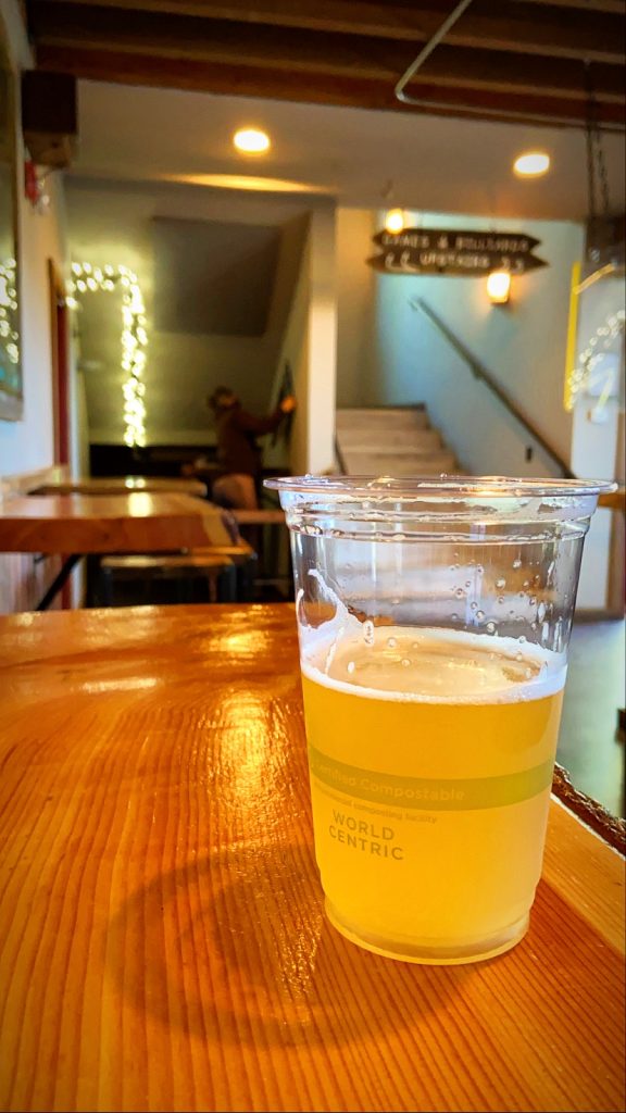 A plastic cup of beer on the table inside of outlaw brewing