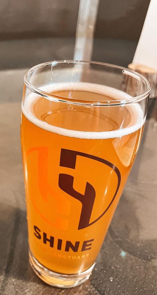 A pint of beer with the Shine beer sanctuary logo placed on a table